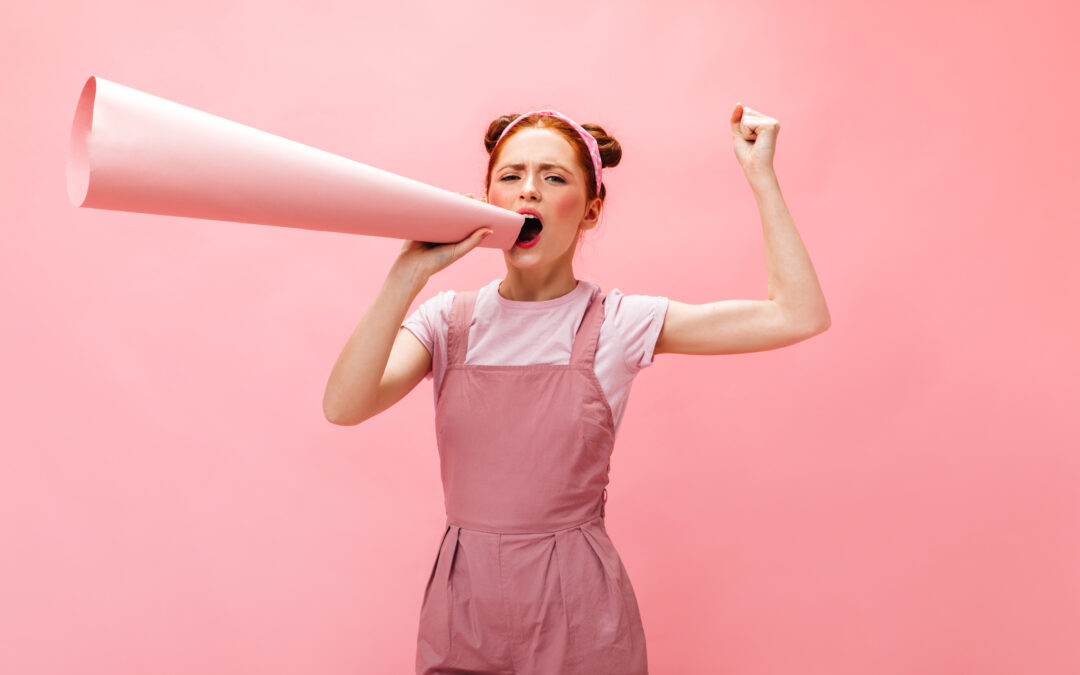 Pink background, woman in overalls, shouting through a funnel